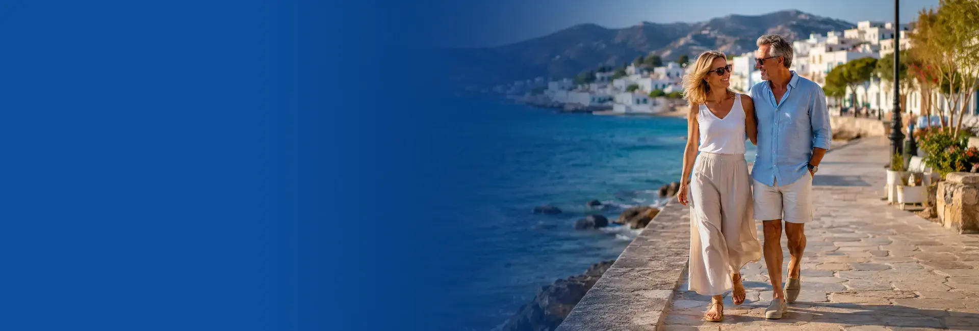 Couple walking along a sunny Mediterranean seafront.